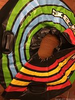 Photo showing two kids snow tubes made of inflatable material with colorful striped patterns and black plastic handles for gripping.