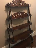 Full view of the 4-tier wooden Victorian style shelf showing carved backboards and turned columns.