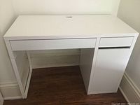 Front view of white Ikea computer desk showing drawer and cabinet door.