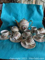 Full view of complete Bavaria tea set arranged on a blue fabric background showing teapot, creamer, sugar, cups and saucers.