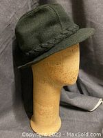 Cork head mannequin wearing a green bucket-style hat with braided detail.