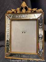 Full view of the etched vintage mirror with gold frame and ornamental top flourish.