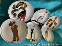 Photo showing all six House of Erte limited edition decorative plates arranged together on fabric background. Plates display various Art Deco stylized female figure designs.