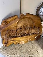 Overall view of the hand carved wooden Last Supper panel showing Jesus and his disciples at the table.
