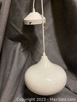 Side view of white glass dome pendant light hanging from cord