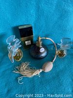 All four perfume bottles displayed on blue cloth: Chanel No. 5, Royal Orchid atomizer, and two frosted crystal bird bottles