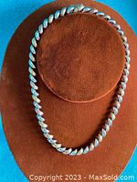 Full view of the twisted sterling silver necklace displayed on a brown stand.