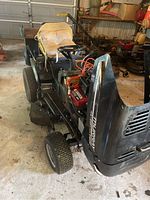 Side view of Murray garden tractor with yellow cushioned seat, showing steering wheel, tires, and wagon attached at rear.