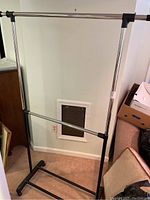 Single metal clothing rack with adjustable height and telescoping bars, featuring black plastic connectors and feet.