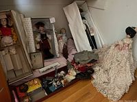 Overview of lot showing multiple dolls, gloves, small figurines, and other assorted items arranged on a surface.
