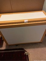 Photo of brown wood framed white laminated expandable buffet table folded compactly