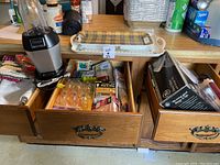 Photo of wooden drawers containing Ninja blender, packaged lightbulbs, hand mixer and iron boxes, and various kitchen items