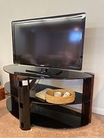 Philips TV on black glass and wood TV stand with woven basket visible.