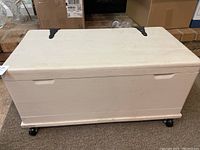 Closed view of white wooden chest on caster wheels