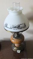 Photo of a bedroom table lamp with solid maple wood turned base and white opaque glass shade with a printed classic winter scene.