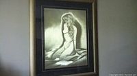Front view of large brass etching of nude woman sitting, framed in heavy wooden frame with low reflection glass.