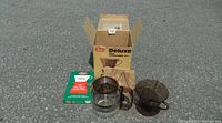 Photo shows original Melitta coffee pot system including glass pot with black handle, brown plastic filter cone, measuring scoop, hot element spacer, green box of paper filters, all in open original cardboard box.