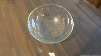 Top view of a clear glass fruit bowl with an 11 inch diameter on a wooden surface.