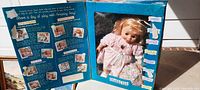 Photo of the open blue Amazing Amy doll box showing the doll dressed in pink and the interior printed with activity images and descriptions.