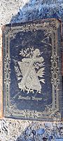 Front cover of antique hardcover religious book showing blue cover with gold embossing featuring a cross, floral elements, and the name Rosalie Boyer.