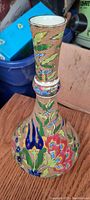 Oblique front view of the antique Japanese vase showing colorful floral enamel with textured surface on the bulbous body.