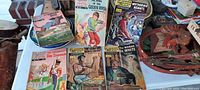 Lot of 6 old comic books displayed standing and lying on a table, showing colorful vintage covers featuring various illustrated classic stories.