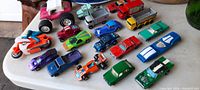 Group view of 22 small tin and diecast vehicles including motorcycles, trucks, and cars in various colors on a white surface.