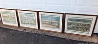 Full set of 4 framed prints depicting military battle scenes of George Washington's army laid out in a row on pavement.
