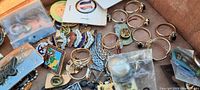 Box containing assorted costume jewelry including rings, pins, belt buckle, necklace, and pendants.