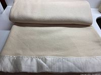 Folded merino wool blanket showing butter cream wool with satin edge binding.