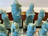 Close-up of celadon green carved chess pieces showing detailed figures
