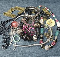 Photo showing the full assortment of mixed boho jewelry including necklaces, bracelets, earrings, pendants and a brooch with detailed view of colors and materials.