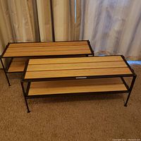 Two bamboo shelving units with black metal frame and bamboo wood shelves shown together, placed on carpet in front of curtains.