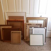Photo showing all nine frames stacked together against a door, displaying a range of sizes and styles including wood and metal frames with vintage and modern looks.
