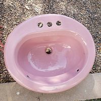 Top view of pink porcelain sink showing three faucet holes, overflow hole, and glossy finish.