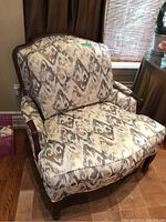 Front angled view of bergere-style armchair showing loose seat and back cushions and wood frame
