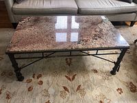 Top view of the coffee table showing the polished marble surface with mixed beige, pink, and black colors and pattern.