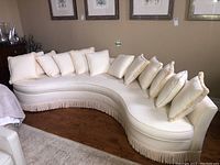 Overall view of curved sofa on hardwood floor showing shape and throw pillows