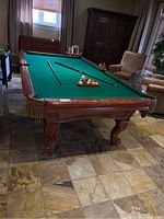 Side view of pool table showing green felt, cues and balls on table