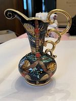 Decorative vase showing shape, gold handles, and colorful floral and geometric painted designs