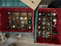 Two crates filled with assorted Christmas ornaments organized in cardboard dividers inside each crate.