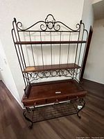 Side angle view of a wooden and metal wine rack hutch showing shelves, metal wine bottle holders, and wooden drawers