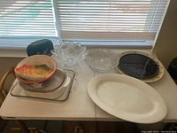 Overview of various serving dishes and bowls on table, including clear glass items and colorful bowls with leaf designs