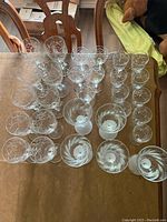 Top-down view of multiple clear etched glass stemware and smaller glasses arranged on a table.