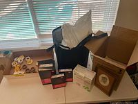 Top-down view of assorted medical cushions, wrist/ankle braces, boxes of Medline Special Brace supports, black insulated tote bag, and a framed clock off to the side.