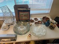 Photo of kitchen glassware including glass bowls, wooden trays, ceramic cups, decorative flowers, and a wall art kit.