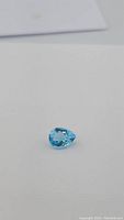 Clear view of the pear-shaped Swiss blue topaz gemstone against a white background, showing its bright blue color and faceting.
