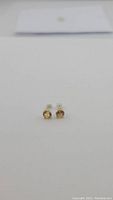 Pair of round golden citrine stud earrings against white background, front view.