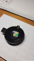 Triangular opal cabochon in black dish showing play-of-color