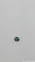 Oval olive green sapphire centered on white background, top-down view.